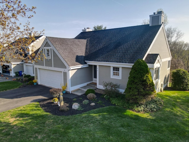 view of front of house with a front lawn, roof with shingles, driveway, and a chimney