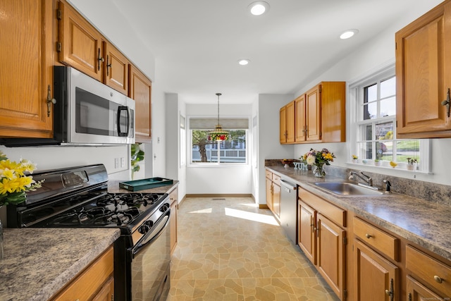 kitchen featuring appliances with stainless steel finishes, a healthy amount of sunlight, baseboards, and a sink