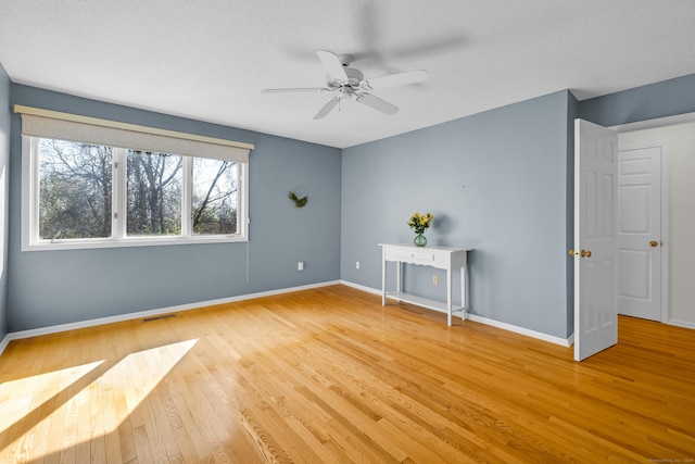 spare room featuring a ceiling fan, visible vents, light wood-style flooring, and baseboards
