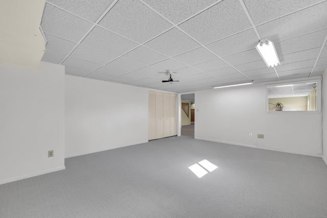 finished below grade area featuring baseboards, carpet, and a paneled ceiling