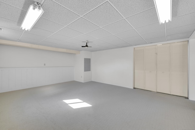 finished below grade area with a drop ceiling, a wainscoted wall, and carpet floors