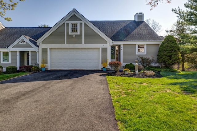 view of front of home featuring driveway, a chimney, roof with shingles, a front yard, and a garage