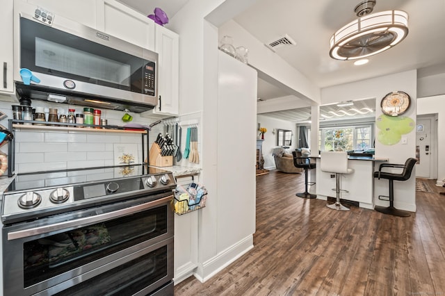 9 Berkshire Dr, Danbury, CT 06811 - kitchen with dark wood-style flooring, a kitchen bar, white cabinets, appliances with stainless steel finishes, and backsplash