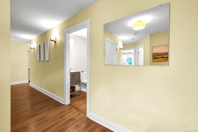 corridor featuring baseboards and wood finished floors