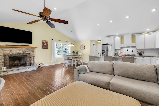 living area featuring dark wood-style flooring, a ceiling fan, baseboards, and a fireplace