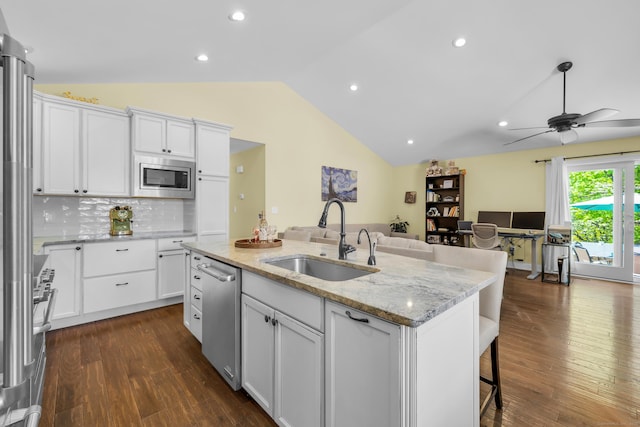 kitchen featuring a sink, stainless steel appliances, open floor plan, vaulted ceiling, and a center island with sink