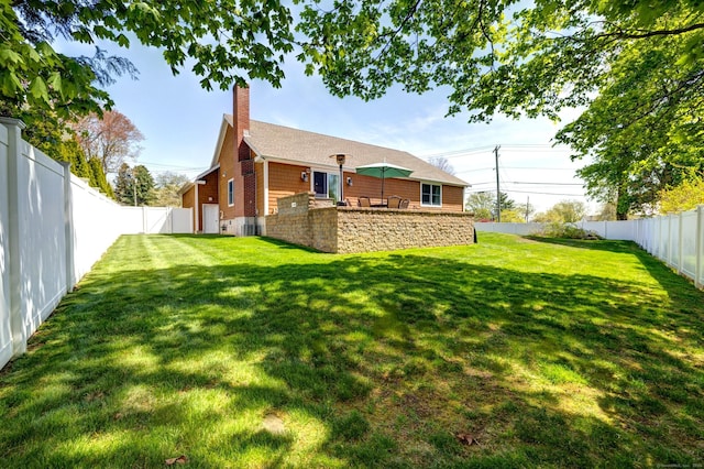 back of property featuring a lawn, a chimney, and a fenced backyard