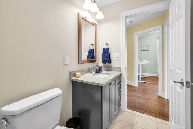 half bath with toilet, baseboards, tile patterned flooring, and vanity