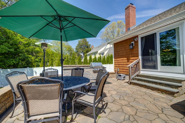 view of patio with fence, a grill, an outdoor kitchen, entry steps, and outdoor dining space