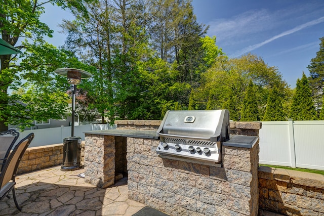 view of patio featuring an outdoor kitchen, a fenced backyard, and a grill