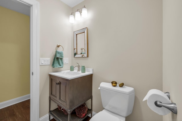 bathroom featuring vanity, baseboards, wood finished floors, and toilet