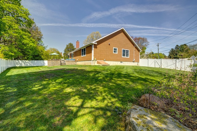 rear view of house with a fenced backyard, a chimney, and a lawn