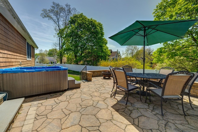 view of patio with fence, outdoor dining space, and a hot tub