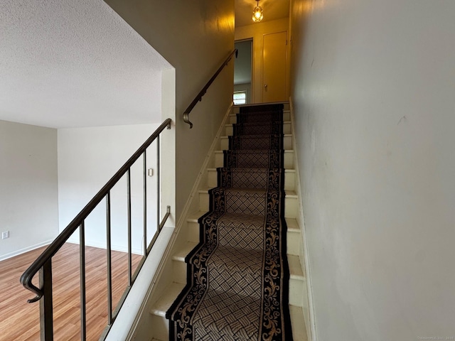136 Westbury Park Rd Apt C, Watertown, CT 06795 - stairway featuring wood finished floors, a textured ceiling, and baseboards