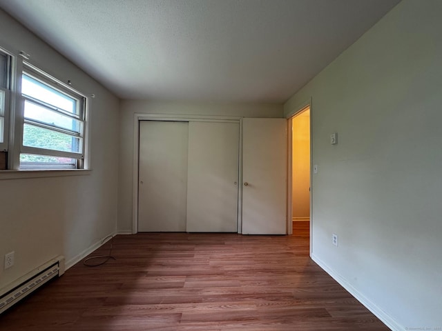 136 Westbury Park Rd Apt C, Watertown, CT 06795 - unfurnished bedroom with baseboard heating, wood finished floors, a closet, and baseboards