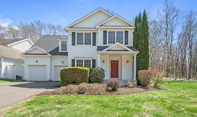 traditional-style house with a garage, a shingled roof, driveway, and a front yard