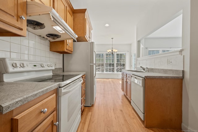 kitchen with tasteful backsplash, an inviting chandelier, white appliances, light wood-style floors, and a sink