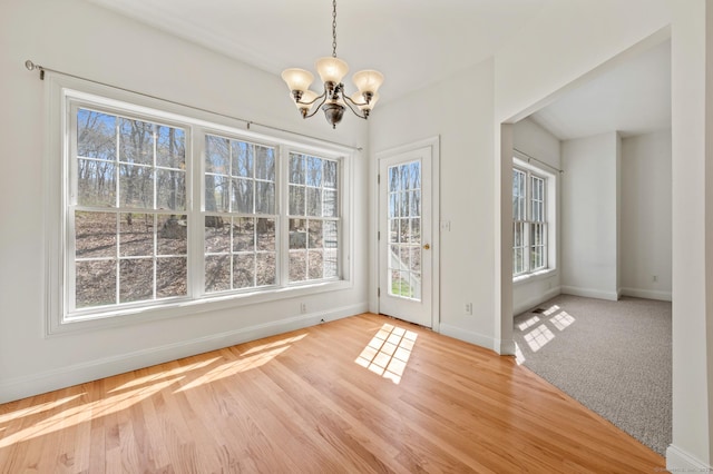 unfurnished dining area featuring an inviting chandelier, light wood-style floors, plenty of natural light, and baseboards