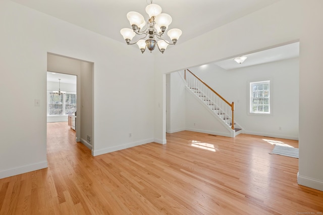 unfurnished dining area with stairway, light wood finished floors, a notable chandelier, and baseboards
