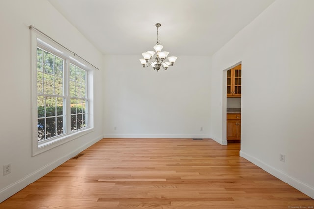 unfurnished dining area with baseboards, a chandelier, and light wood-style floors