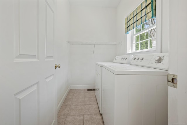 laundry area featuring light tile patterned floors, washer and clothes dryer, laundry area, and baseboards
