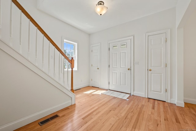 foyer featuring light wood finished floors, stairs, visible vents, and baseboards