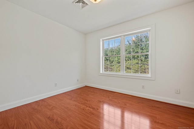 unfurnished room featuring visible vents, wood finished floors, and baseboards