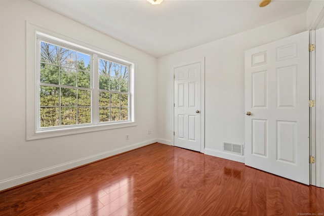 unfurnished bedroom with wood finished floors, visible vents, and baseboards