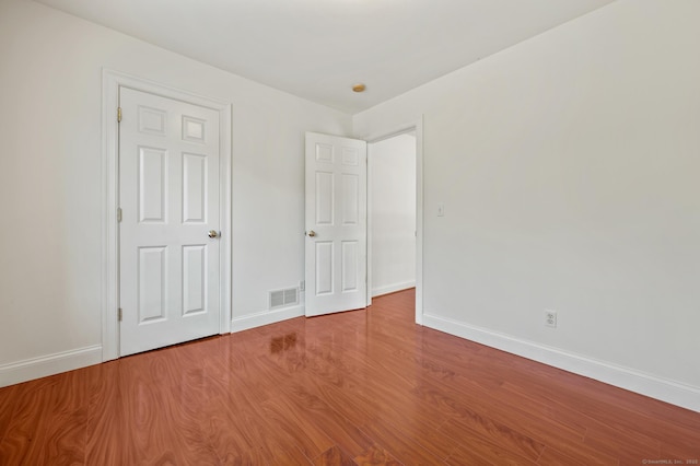 unfurnished bedroom featuring wood finished floors, visible vents, and baseboards