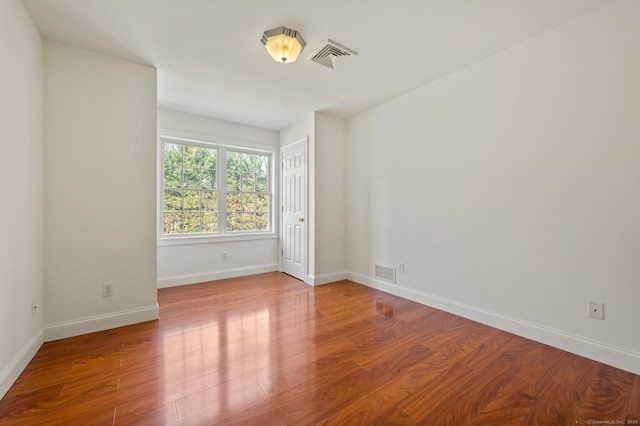 empty room with visible vents, wood finished floors, and baseboards