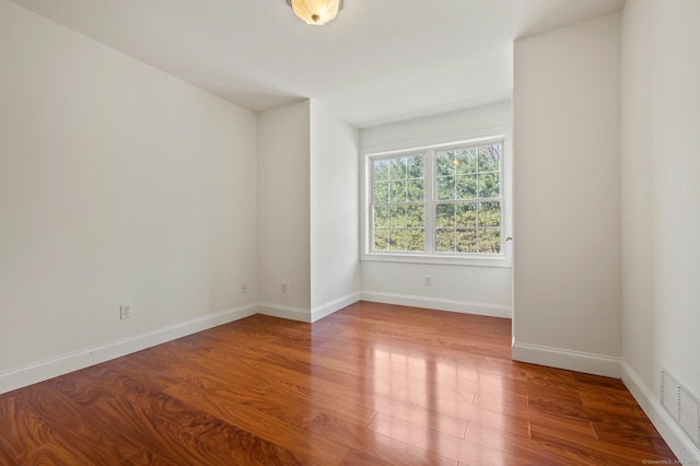 spare room with visible vents, wood finished floors, and baseboards