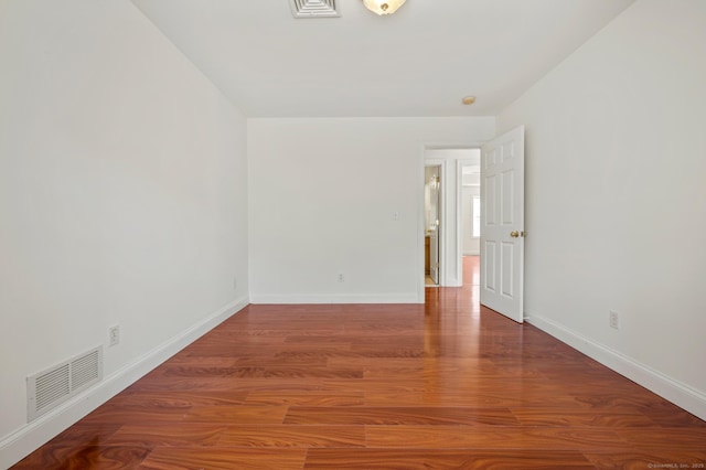 unfurnished room with baseboards, visible vents, and wood finished floors