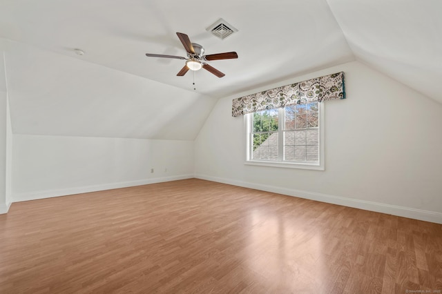 additional living space with light wood-type flooring, a ceiling fan, visible vents, baseboards, and lofted ceiling