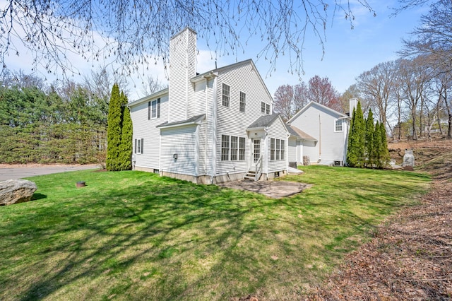 rear view of property with a chimney, a yard, and entry steps