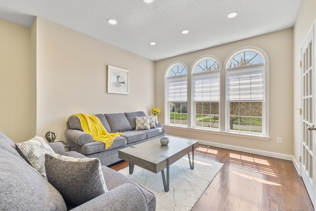 living room with recessed lighting, a textured ceiling, wood finished floors, and baseboards