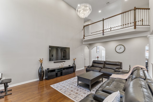 living area featuring a towering ceiling, visible vents, baseboards, and arched walkways