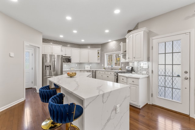 kitchen featuring white cabinetry, a sink, stainless steel appliances, a kitchen island, and dark wood-style floors