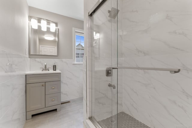 bathroom featuring tile walls, vanity, wainscoting, and a marble finish shower