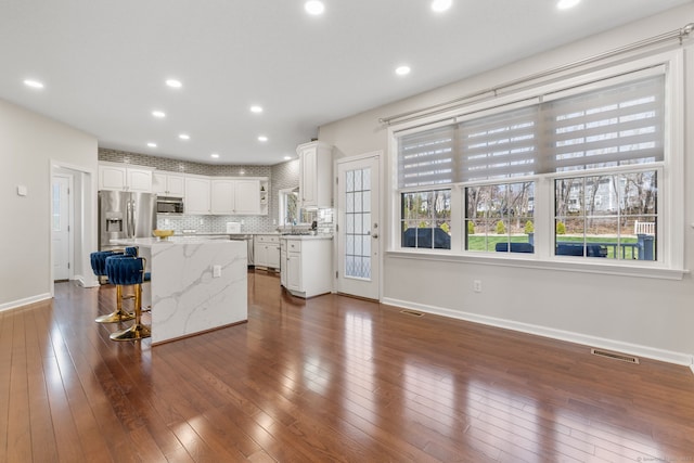 kitchen featuring visible vents, stainless steel appliances, a kitchen island, and white cabinets