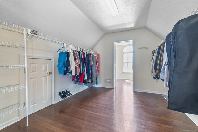 spacious closet with lofted ceiling, visible vents, and hardwood / wood-style floors