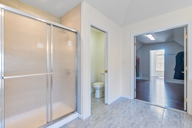 bathroom with a stall shower, baseboards, toilet, vaulted ceiling, and tile patterned floors