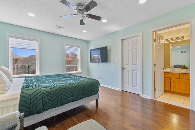 bedroom with a sink, visible vents, baseboards, recessed lighting, and wood finished floors