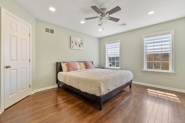 bedroom with baseboards, visible vents, and wood finished floors