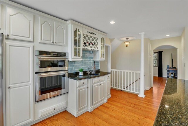 496 Foote Rd, Glastonbury, CT 06073 - kitchen featuring decorative backsplash, glass insert cabinets, a sink, arched walkways, and stainless steel double oven