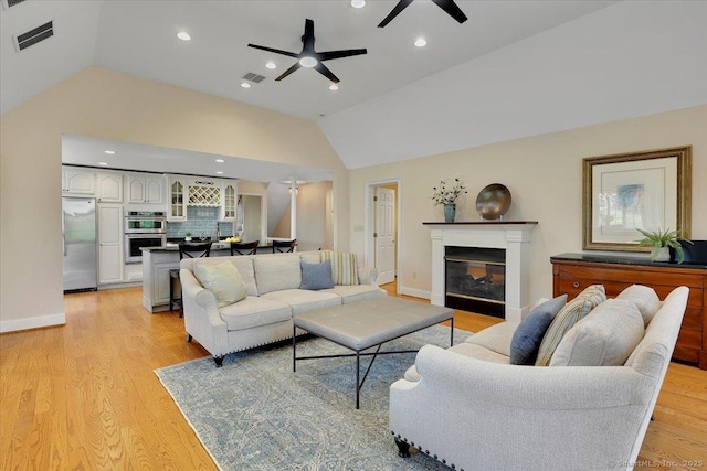 496 Foote Rd, Glastonbury, CT 06073 - living area with a glass covered fireplace, a ceiling fan, visible vents, light wood-style flooring, and lofted ceiling