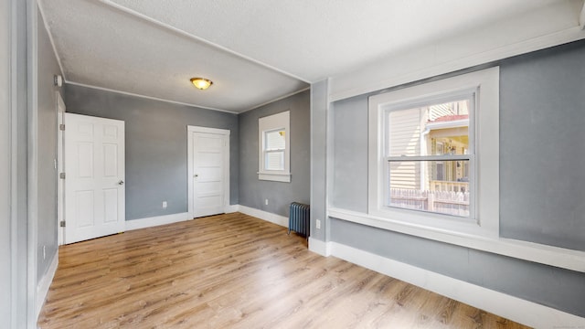 40 Penobscot St, Norwich, CT 06360 - unfurnished bedroom with baseboards, radiator heating unit, wood finished floors, and multiple windows