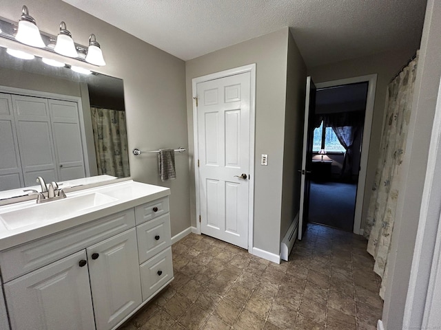 full bath with vanity, baseboards, and a textured ceiling