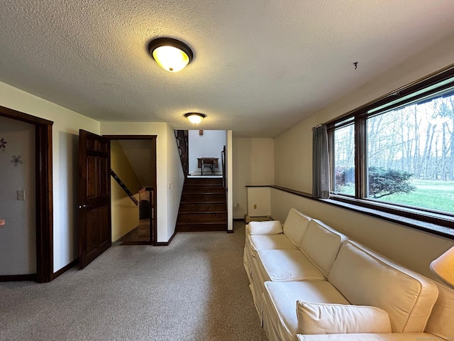 living room featuring stairway, baseboards, a textured ceiling, and light colored carpet