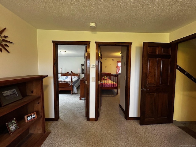 corridor with light carpet and a textured ceiling