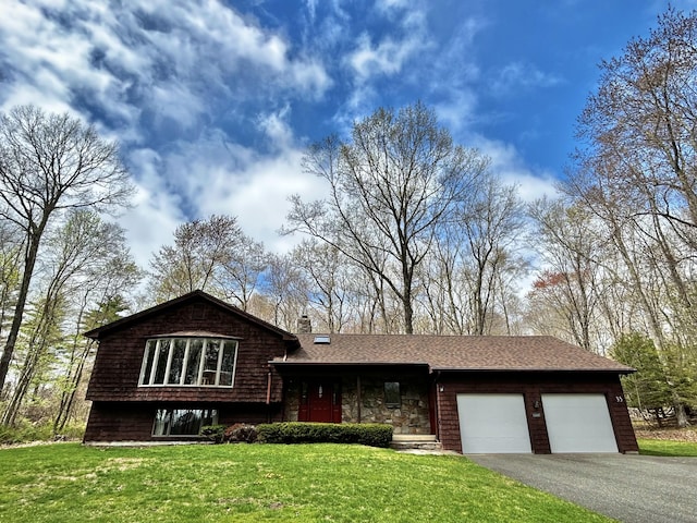 tri-level home featuring driveway, a chimney, a front yard, and a garage